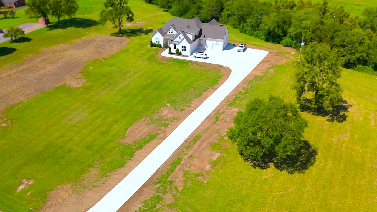 Finished concrete driveway curving toward a white home